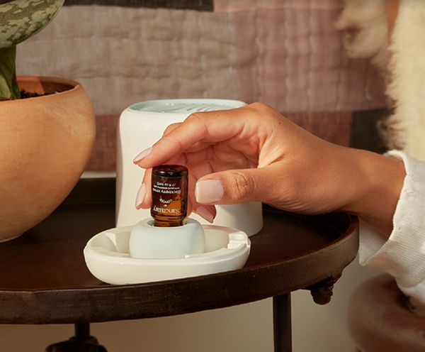 A photo of an essential oil diffuser and bottles of essential oils in a bathroom.