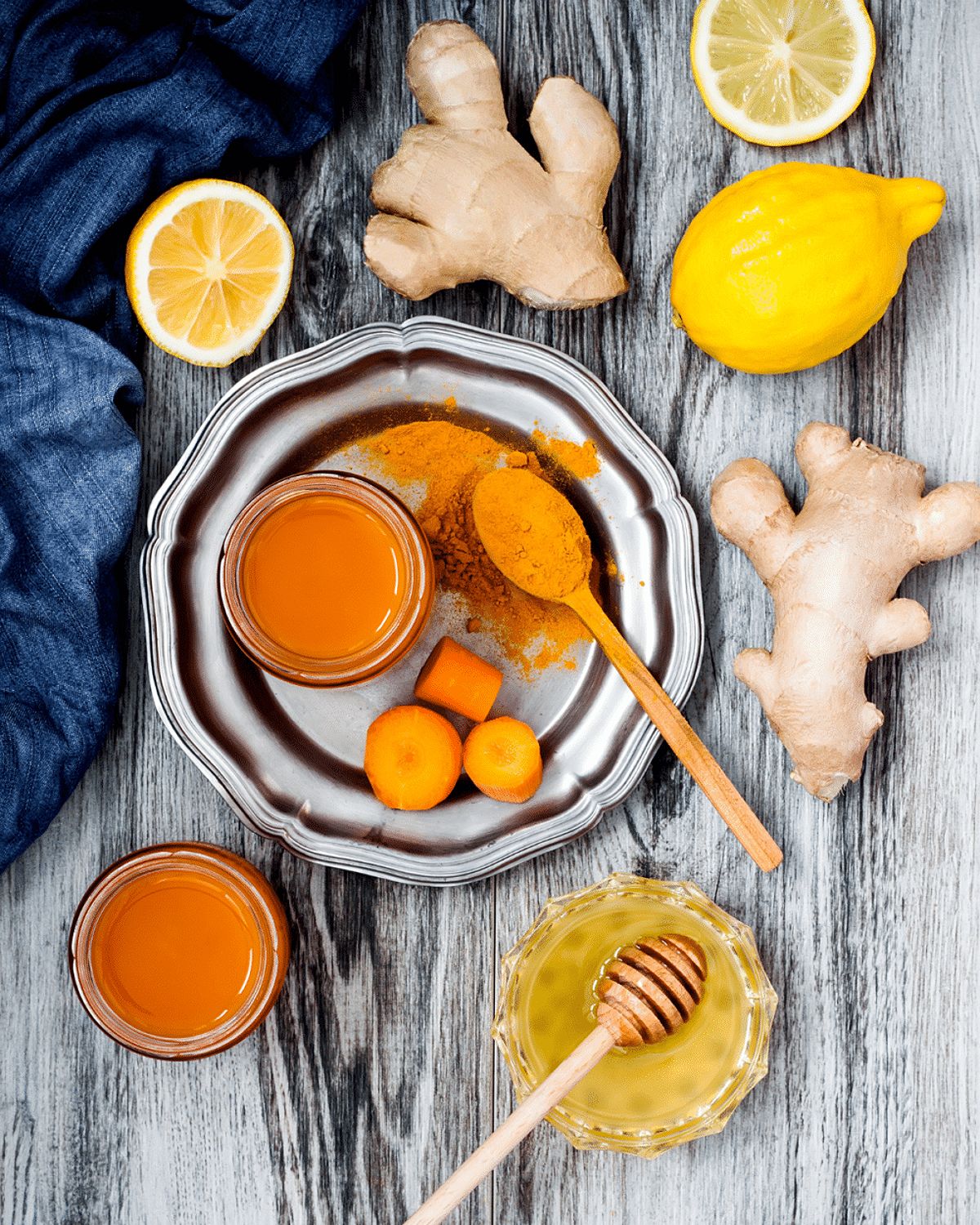 Anti-Inflammatory ingredients like ginger, lemon, turmeric, lemons and carrots on a gray wooden table