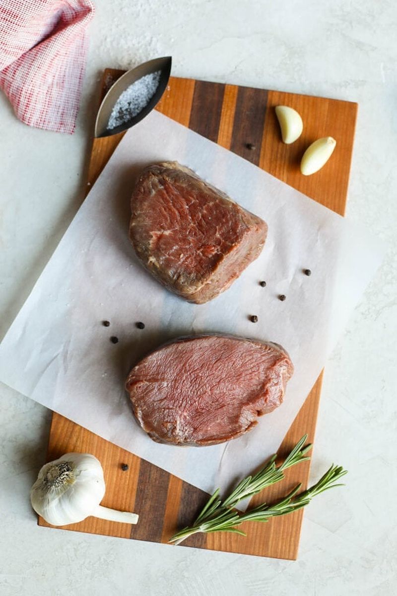 Raw grass fed beef steaks on parchment paper on cutting board