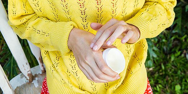 Young girl rubbing skin repair cream into her hands